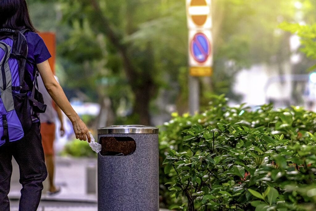 Why Is Singapore So Strict? 24 Rules To Know Before Visiting 4 Woman Throwing Plastic Bottle In Garbage Can