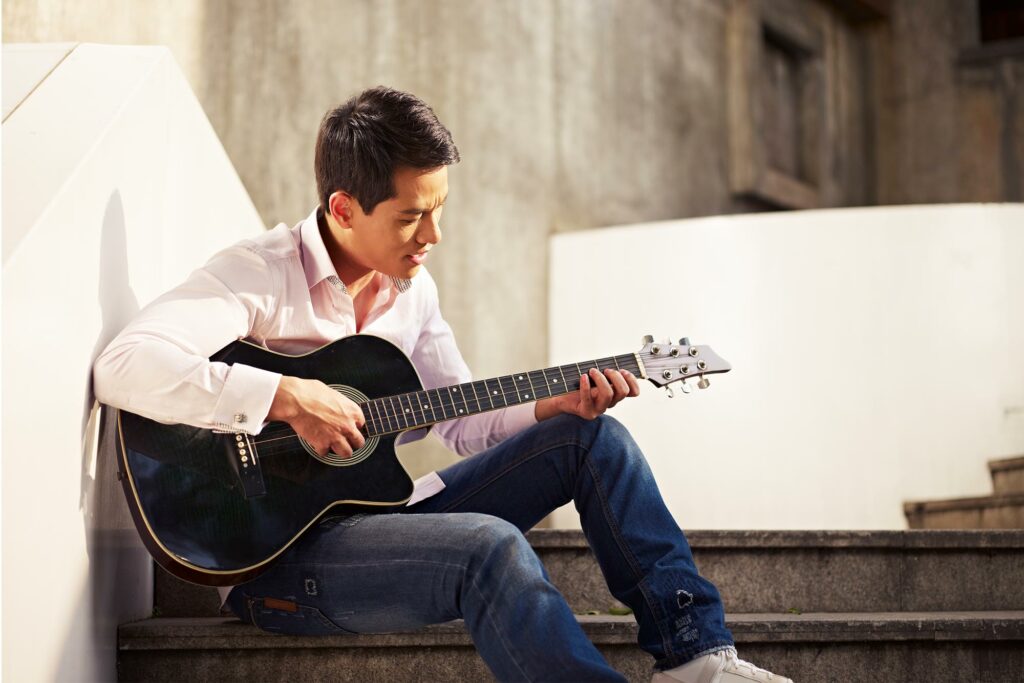 Man Sitting On Steps Playing Guitar Singing